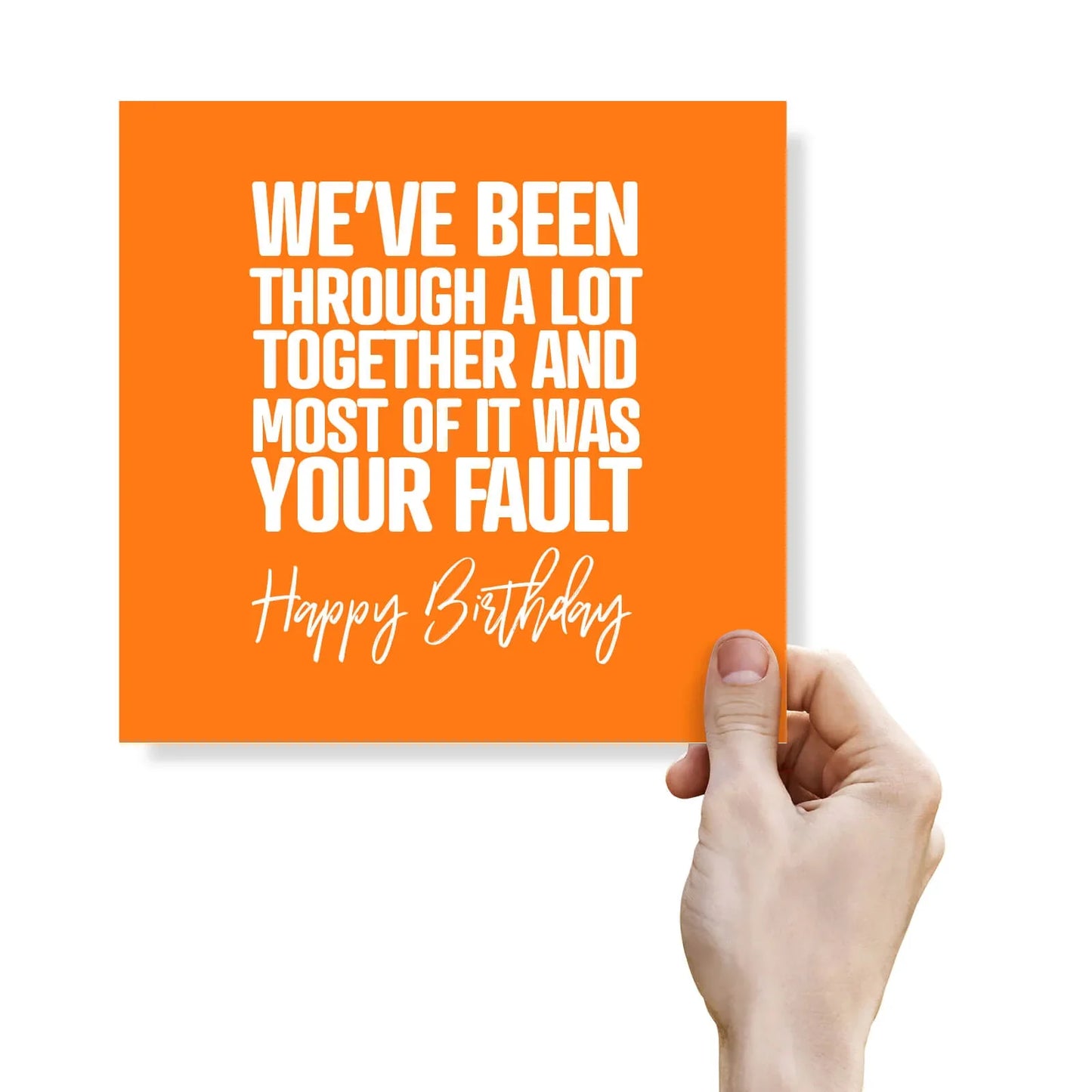 Hand holding an orange card with humorous birthday message on a white background