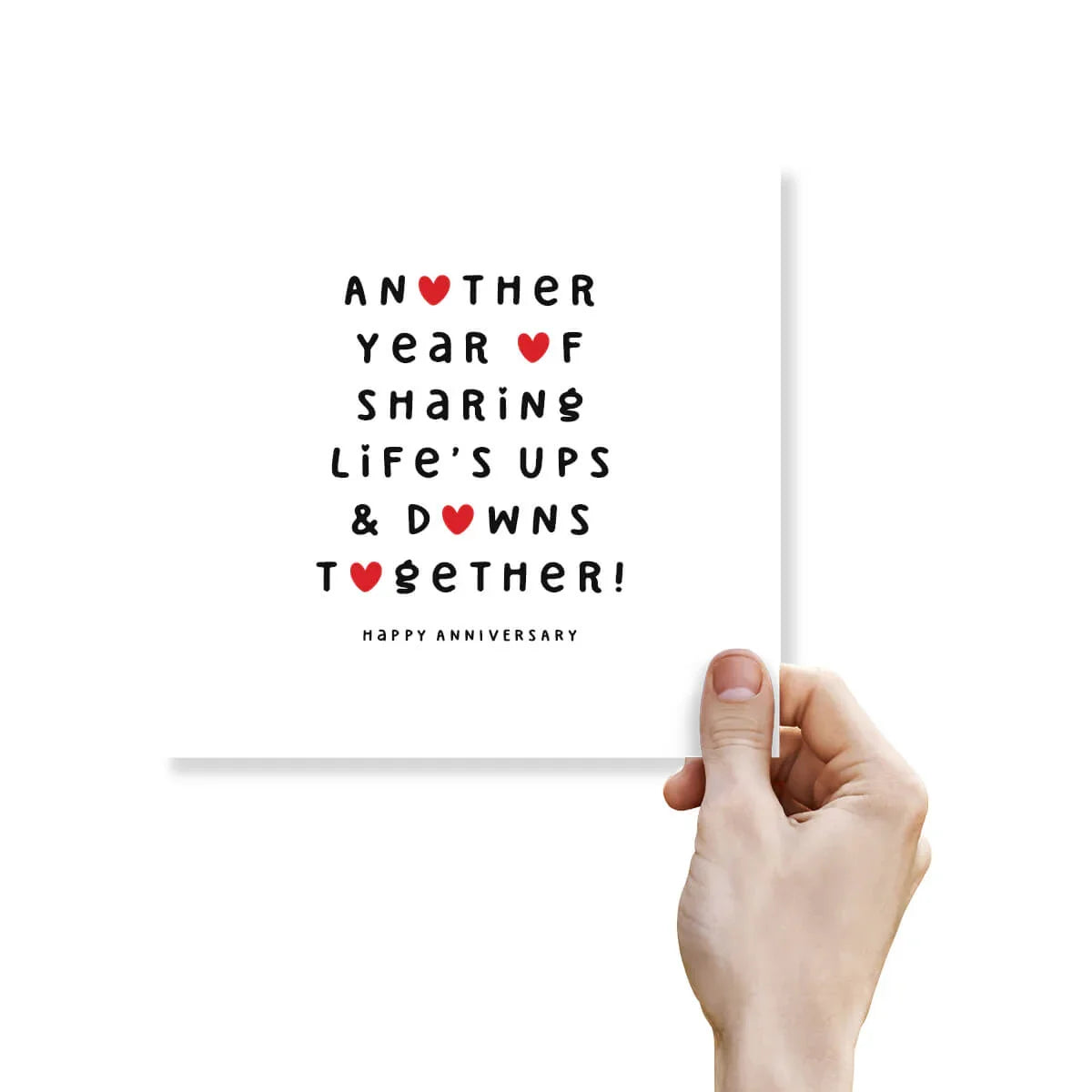 Funny anniversary card with bold black text and red heart icons, held in hand, white background.