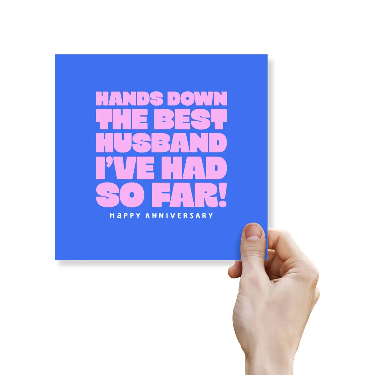 Funny anniversary card with bold pink text on blue saying 'Hands down the best husband I’ve had so far! Happy Anniversary,' held by a hand.