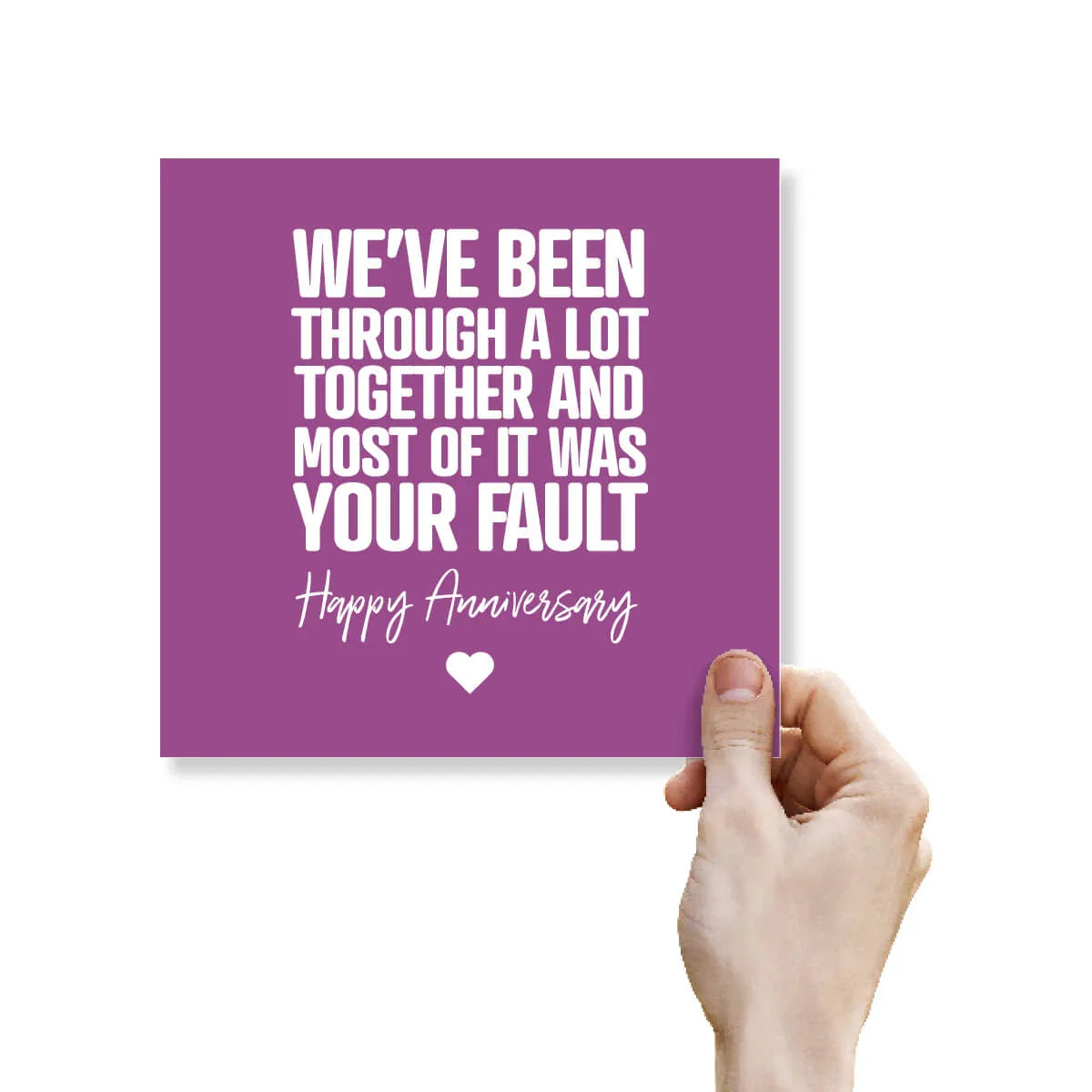 Purple card with white text 'We've been through a lot together and most of it was your fault. Happy Anniversary' held by a hand on a white background.