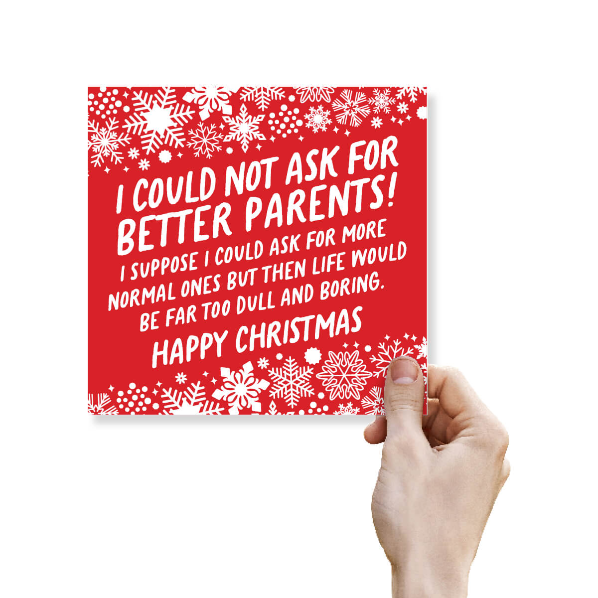 A hand holding a square red Christmas greeting card with white snowflakes and white text that reads, 'I COULD NOT ASK FOR BETTER PARENTS! I SUPPOSE I COULD ASK FOR MORE NORMAL ONES BUT THEN LIFE WOULD BE FAR TOO DULL AND BORING. HAPPY CHRISTMAS' on a white background.
