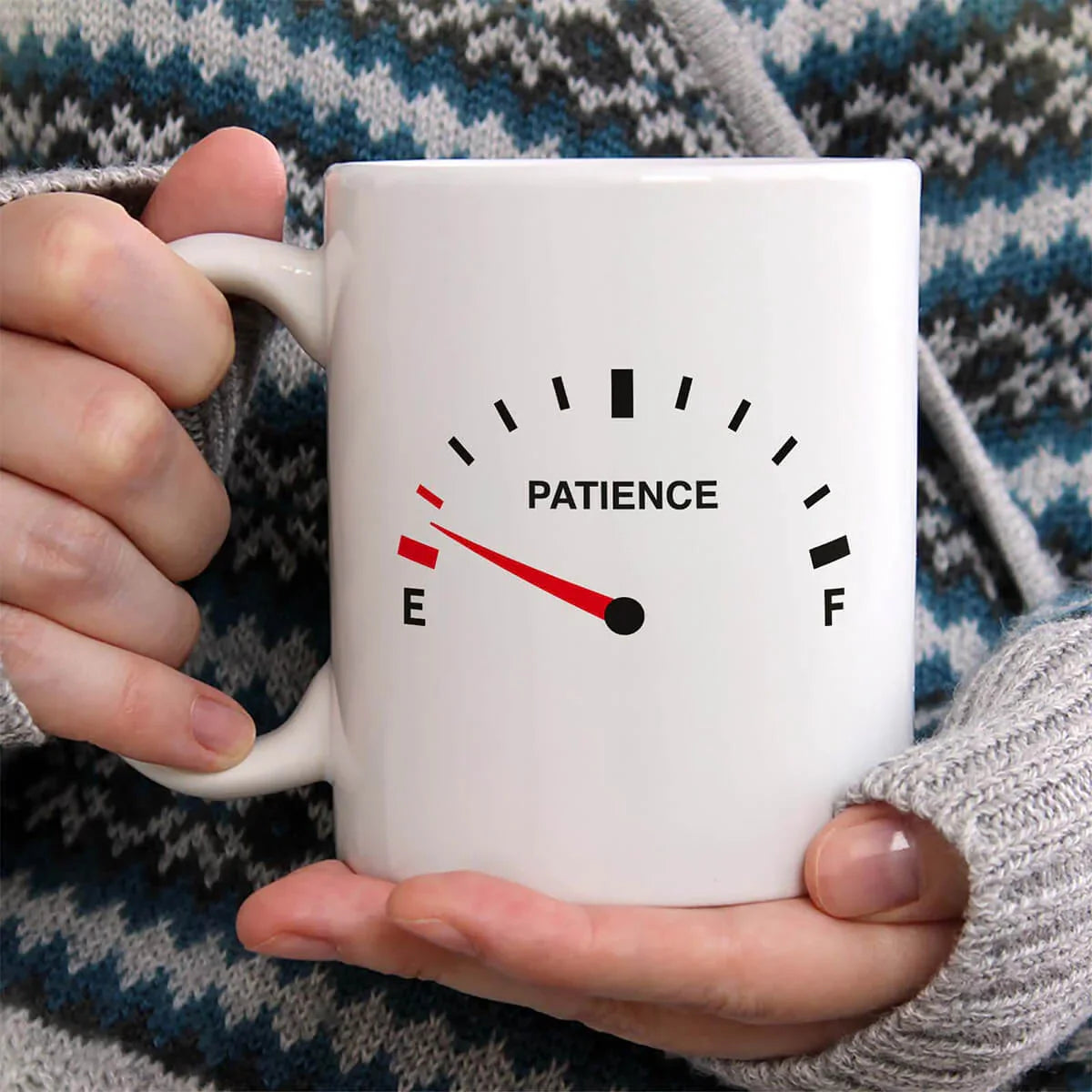 Person holding a mug with a 'Patience' gauge design, indicating low patience level.