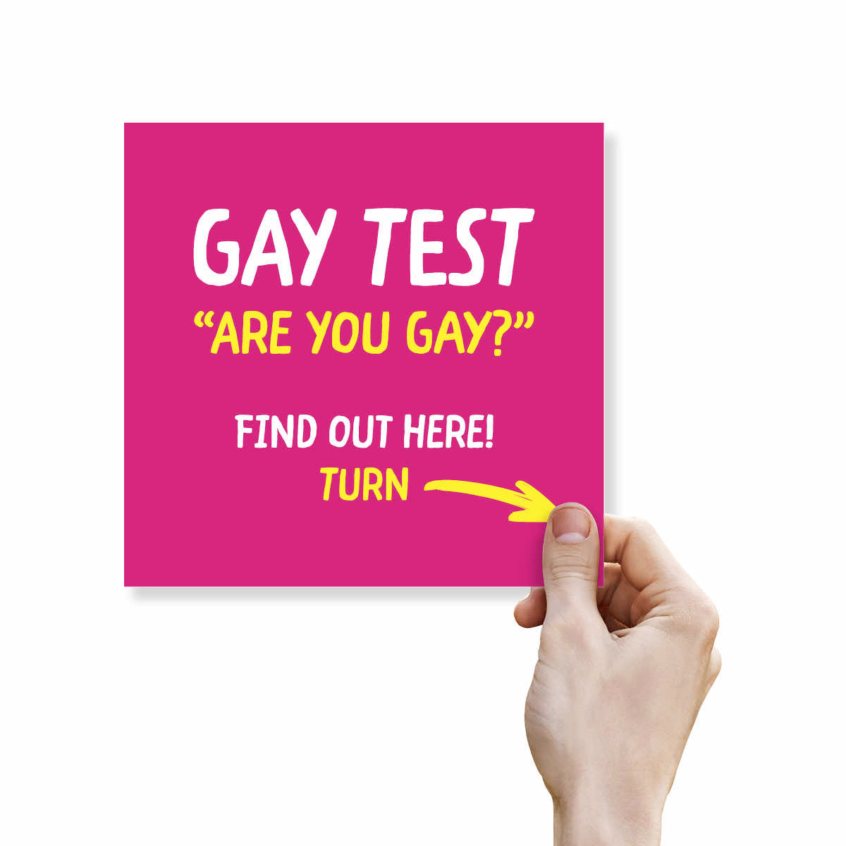 A hand holds a bright pink square card with bold white and yellow text reading “GAY TEST ‘ARE YOU GAY?’ FIND OUT HERE! TURN” with a yellow arrow pointing to the bottom right corner, on a white background.