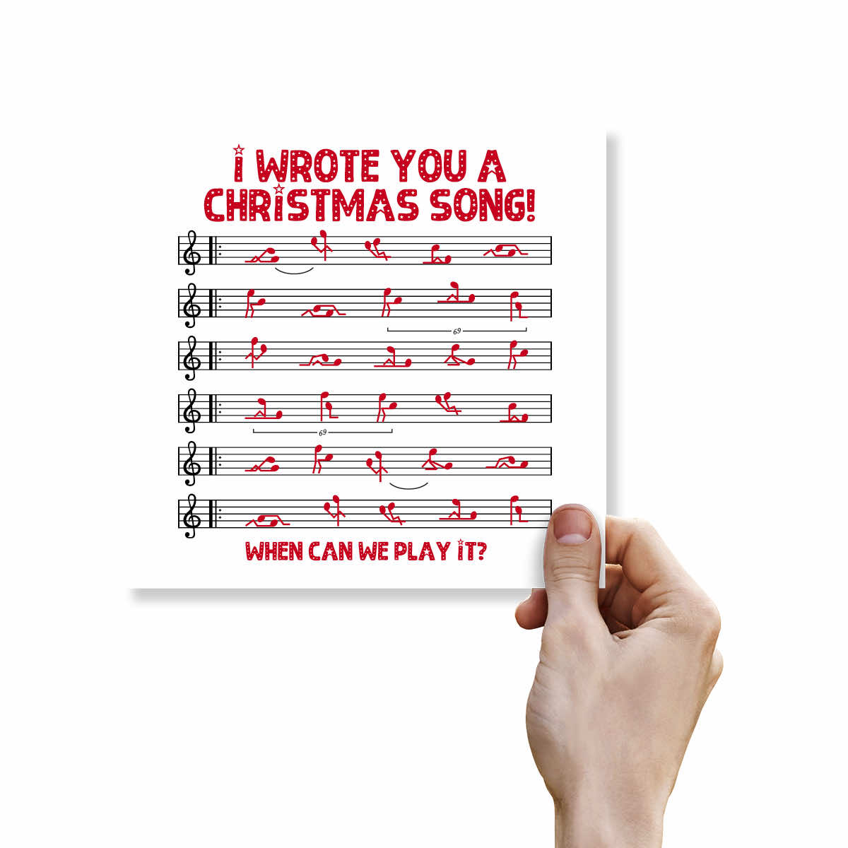 A hand holding a white print featuring red text that reads 'I WROTE YOU A CHRISTMAS SONG! WHEN CAN WE PLAY IT?' above black musical notation on a staff.